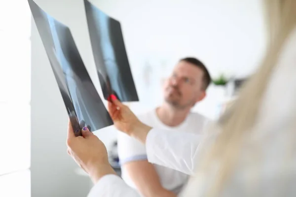 Dokter toont röntgenfoto 's aan patiënt in kliniek closeup — Stockfoto