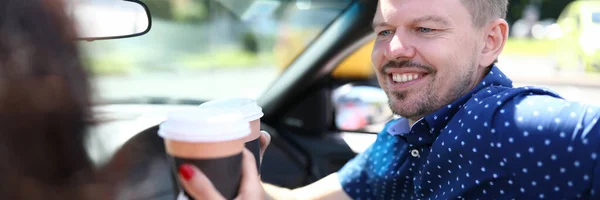 Sonriente hombre bebe bebidas con una mujer en el coche. — Foto de Stock