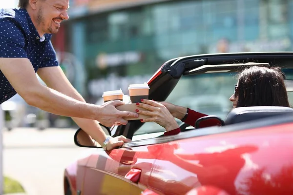 Hombre sirviendo dos vasos de café a mujer en rojo convertible — Foto de Stock