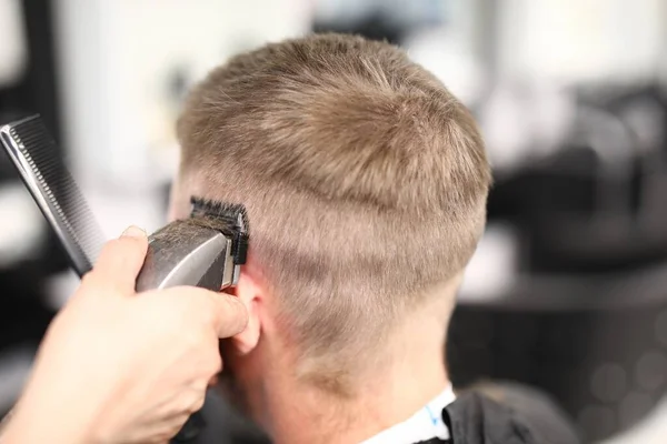 Coiffeur tenant tondeuse à cheveux près de la tête de l'homme gros plan — Photo