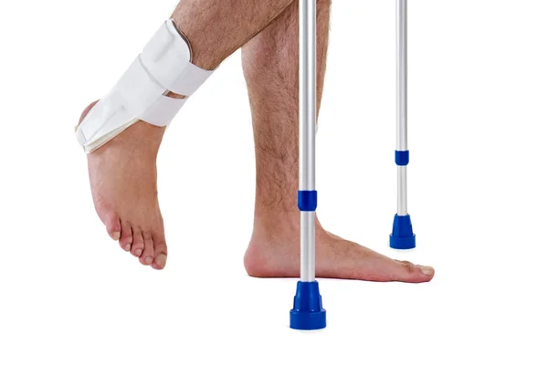 Uomo che indossa cavigliera camminando con le stampelle — Foto Stock