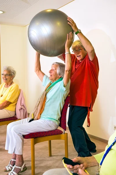 Tränare och kvinna lyfta stabilitets-ball — Stockfoto