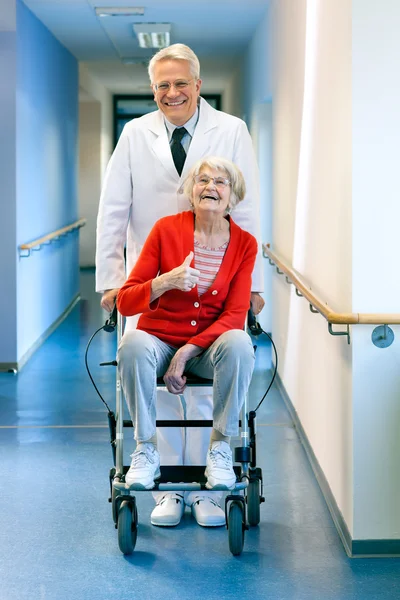 Доктор толкает пожилую женщину в инвалидном кресле . — стоковое фото