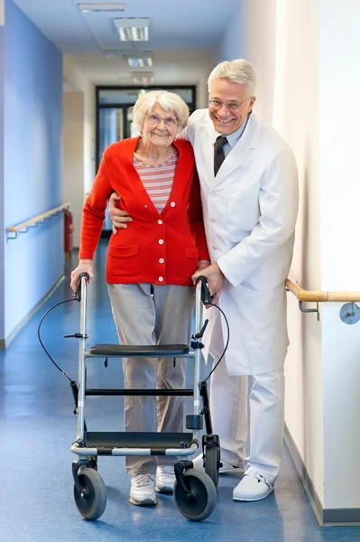 Arts helpen een senior vrouw in een walker. — Stockfoto