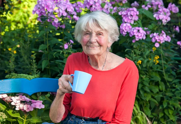 Старшая женщина в саду пьет чай — стоковое фото