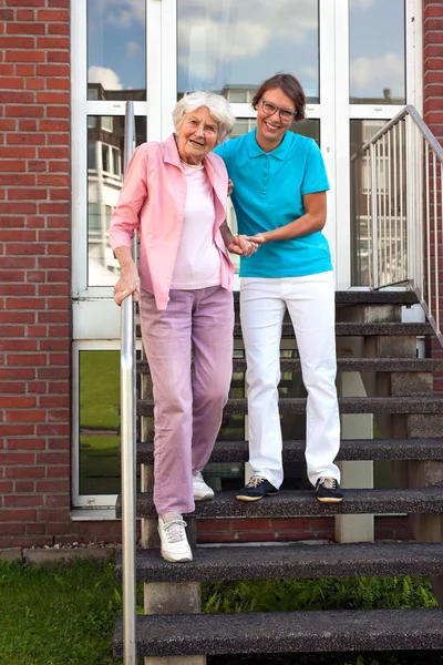 Vård assistent att hjälpa damen på stegen — Stockfoto