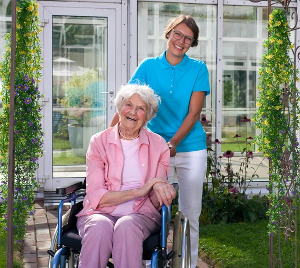 Äldre dam i rullstol med omsorg assistent — Stockfoto