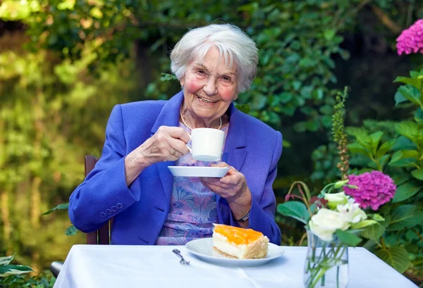 Starszy kobieta siedzi w ogrodzie — Zdjęcie stockowe