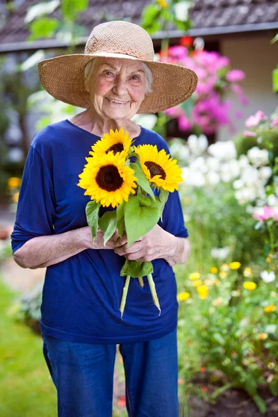 Senior vrouw bedrijf zonnebloemen — Stockfoto