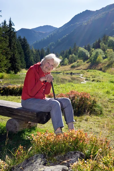 Starší žena sedí na lavičce — Stock fotografie