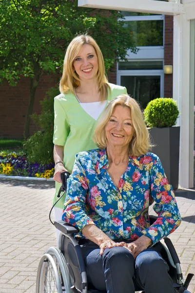 Infirmière poussant la femme en fauteuil roulant — Photo