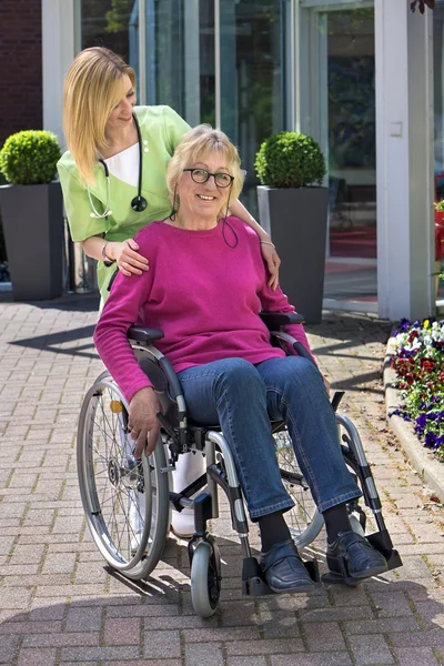 Krankenschwester steht hinter Seniorin — Stockfoto