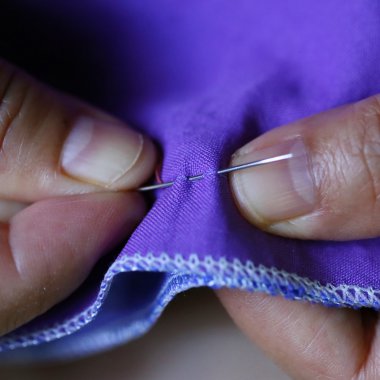 Yakın plan kadınlar, mor kumaş ve iğne dikiyorlar.