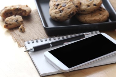 Masada kahve bisküvisi ve kalemle defter, ev ofis kavramı.