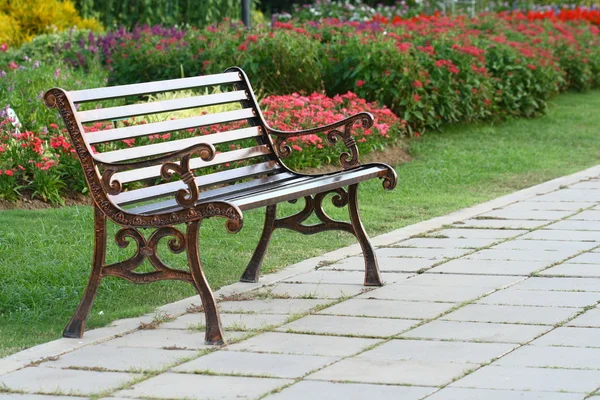 Brown chair in a flowers garden with walkway — Stock Photo, Image