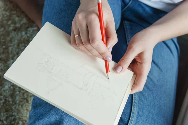 A pencil in a woman's hands. Drawing on sheet of paper with a simple pencil. The concept of creativity and drawing.