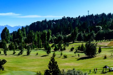 Öğleden sonra Bariloche 'deki golf sahasında. Yaz günü ve golf. Çamlar ve dağlar.