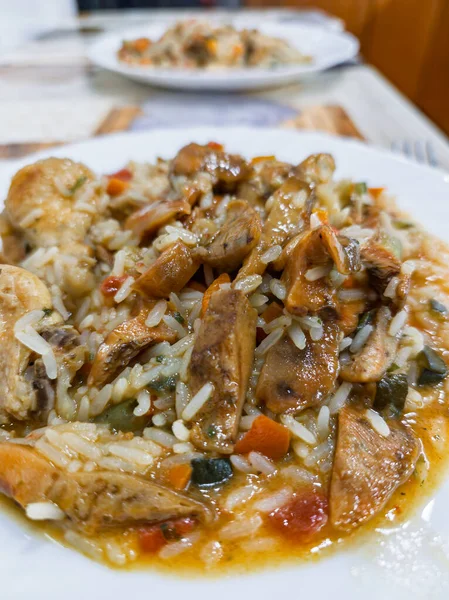 Et ve sebzeli bir tabak pirinç. Pirinç kahverengi ve et kahverengidir. Sebzeler turuncu ve yeşil.