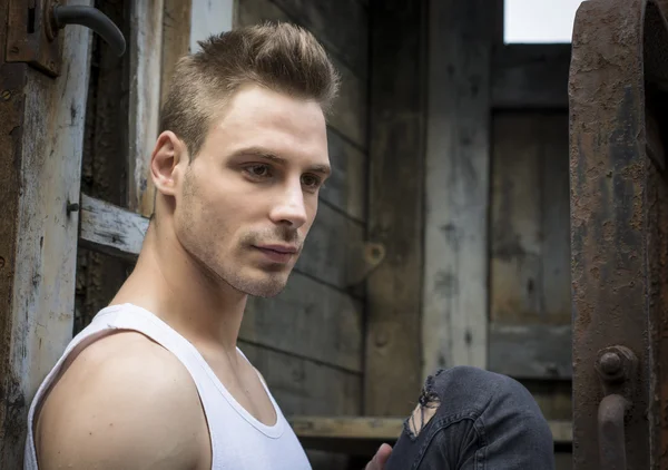 Handsome young man outdoor, with rusty and old walls behind — Stock Photo, Image