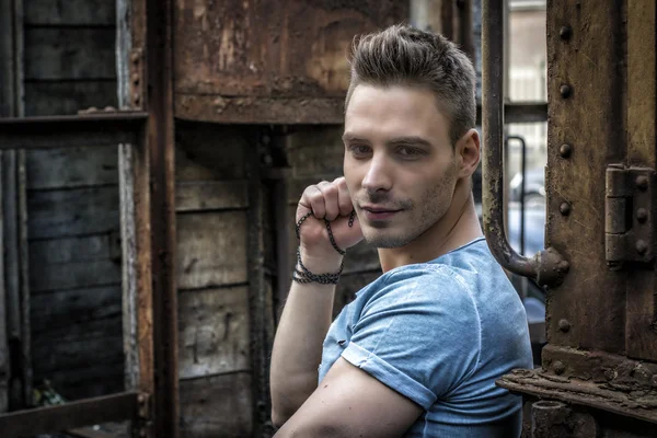 Young man sitting against old rusty train — Stock Photo, Image