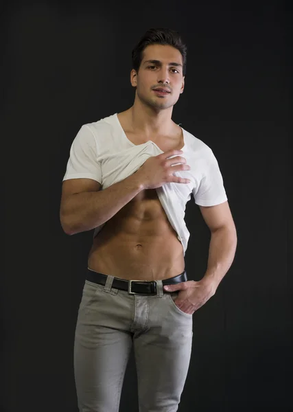 Lekkoatletycznego młody mężczyzna wyciągając biały t-shirt pokazać abs — Zdjęcie stockowe