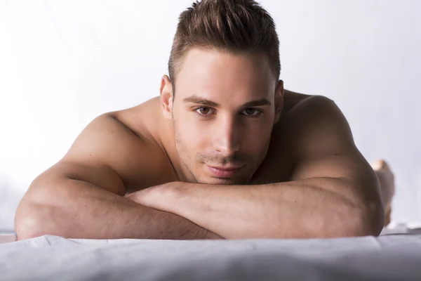 Cute expression, naked young man on white sheets — Stock Photo, Image