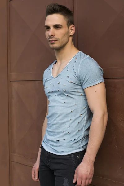 Young man standing against red metal doors — Stock Fotó