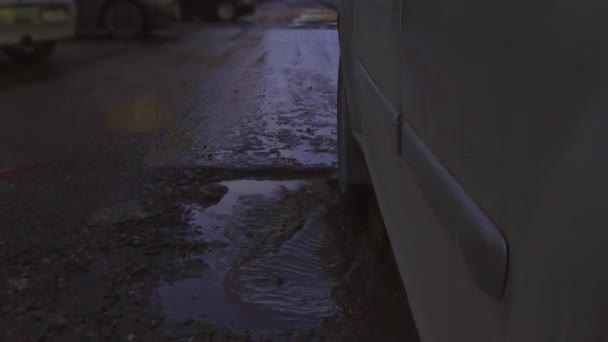 汚れた雨のプールでいっぱいの大きなプールで非常に悪い状態で道路上の車のホイールの閉じる — ストック動画