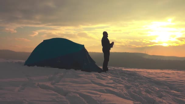 1日のハイキングの後 テントの前 雪の多い冬の山の中で 火山から熱いお茶をお楽しみください — ストック動画