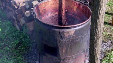 Geleneksel kazanda karıştırıcıyla erik reçeli pişirmek. Erikli reçel hazırlama süreci eski geleneksel açık hava metodu