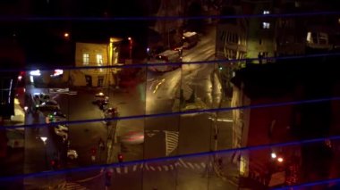 Geceleri sokak trafiği modern cam bir binaya yansıyor. Zaman Uygulaması