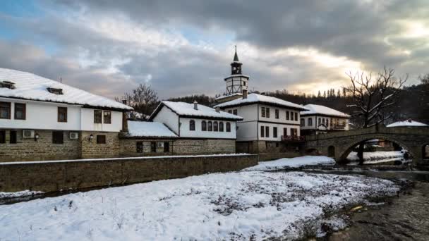 雪に覆われた古い家の上に移動雲と日没前の時間の経過トリャヴナ ブルガリア 4Kの復興建築複合体時間の経過 — ストック動画