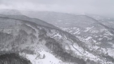 Sisli kış sabahında Balkan Dağları 'nın karla kaplı yamaçlarında insansız hava aracı uçuşu