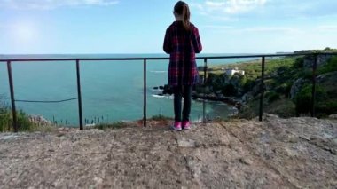 Resimli kayalık kıyı şeridini seyreden bir kızın olduğu İHA videosu. Karadeniz kıyısında bahar zamanı, Yailata - Bulgaristan 'ın ulusal arkeoloji ve doğa rezervi