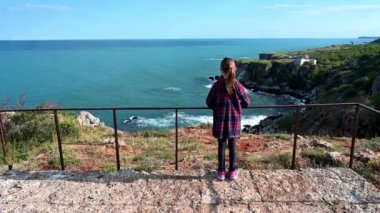 Resimli kayalık kıyı şeridini seyreden bir kızın olduğu İHA videosu. Karadeniz kıyısında bahar zamanı, Yailata - Bulgaristan 'ın ulusal arkeoloji ve doğa rezervi