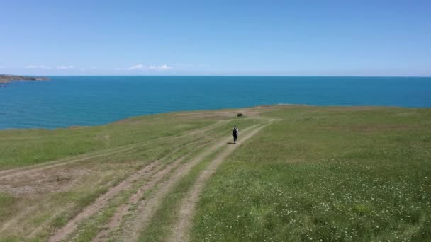 在保加利亚黑海南部海岸 一个背着背包的女人在绿油油 风景如画的海岸线上漫步 无人机在她上方盘旋 — 图库视频影像