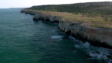 Bulgaristan 'daki Yailata arkeolojik rezervinin insan eliyle tamamlanmış ve M.Ö. bin yılına dayanan doğal mağaralardan oluşan kayalık kayalık kıyı şeridi videosu..