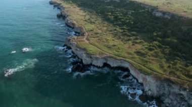 Yeşil alanlar ve ağaçlarla kaplı kayalık kayalık kıyı şeridinin panoramik videosu. Karadeniz kıyısında bahar zamanı, Yailata - Bulgaristan 'ın ulusal arkeoloji ve doğa rezervi