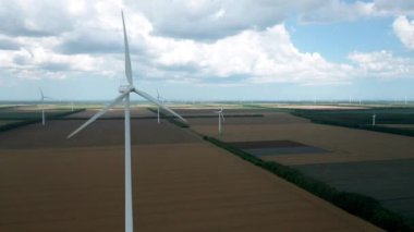 Yaz tarlaları boyunca rüzgar türbinlerinin üzerinde uçan hava. Temiz ve yenilenebilir rüzgar enerjisi çiftliği hareket halinde. Yeşil enerji, sürdürülebilir alternatif elektrik, kirlilik ortamı yok.
