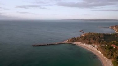 Bulgaristan 'ın Varna kenti yakınlarındaki Karadeniz kıyısında kumlu plajlar ve rıhtımlarla panoramik sabah manzaralı hava videosu.