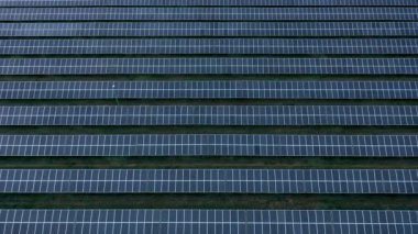 Güneşli bir günde güneş enerjisi üreten bir çiftlikteki güneş panellerinin hava görüntüsü. Yenilenebilir enerji için fotovoltaik modüller