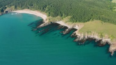 Vahşi plajları, yeşil ormanları ve turkuaz deniz suları olan kayalık bir sahil şeridinde insansız hava aracı uçuşu.