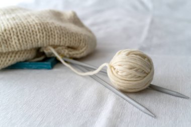 Gri örgü iğneleri, yumuşak odaklı beyaz arka planda kalın yün iplikler oluşturuyordu. Kadın hobisi ve örgü konsepti..