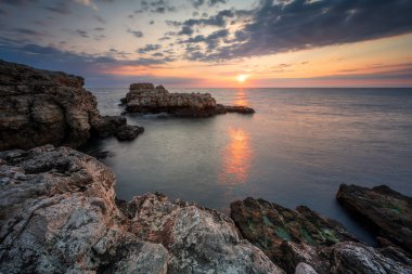 Karadeniz 'in kayalık kıyı şeridinde renkli gündoğumu gökyüzü ile inanılmaz manzara