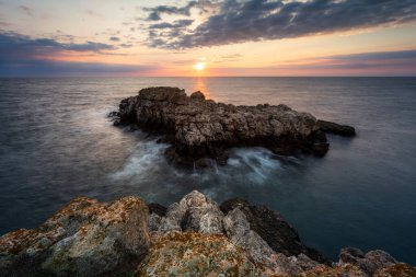 Karadeniz 'in kayalık kıyı şeridinde renkli gündoğumu gökyüzü ile inanılmaz manzara