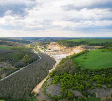 Çalışan makinelerle birlikte açık maden ocağının havadan görünüşü. Yukarıdan görüş. Taş ocakları, mavi gökyüzü inşaatı için. Mayın sektörü geçmişi.