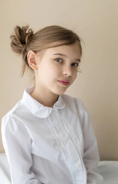 Güzel sarışın, beyaz saçlı, şık saçlı, kot pantolon ve beyaz gömlekli, sakin ve hayalperest görünümlü küçük bir kızın yakın çekimi. 