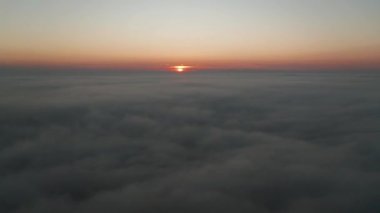 Sabahın bu saatinde alçak bulutlar ve güzel gündoğumuyla kaplı sakin bir deniz manzarası.