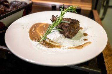 Biftek fileto ile birlikte beyaz tabağın yakın görüntüsü. Baharatlı ve soslu taze et, güzelce yerleştirilmiş ve servis etmeye hazır..