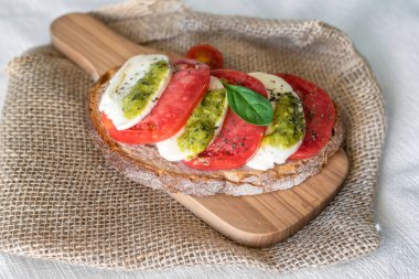 Mozzarella soslu Caprese sandviçi, domates, fesleğen, beyaz arka planda İtalyan ekmeği